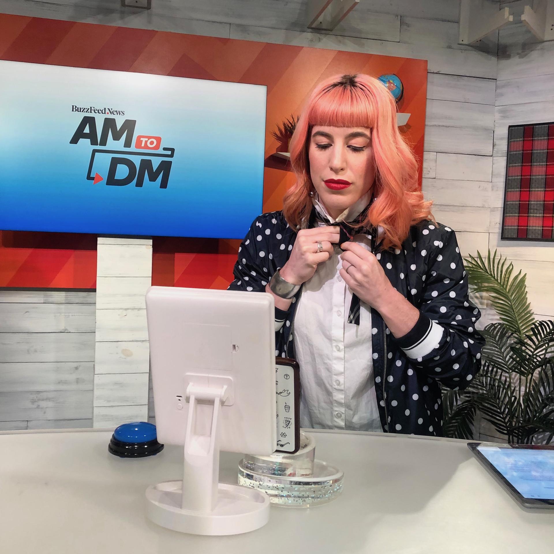 Woman with pink hair tying a bow tie