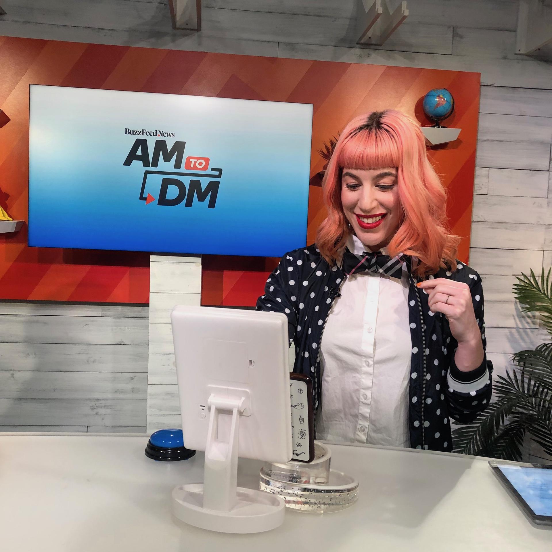Woman with pink hair tying a bow tie and smiling