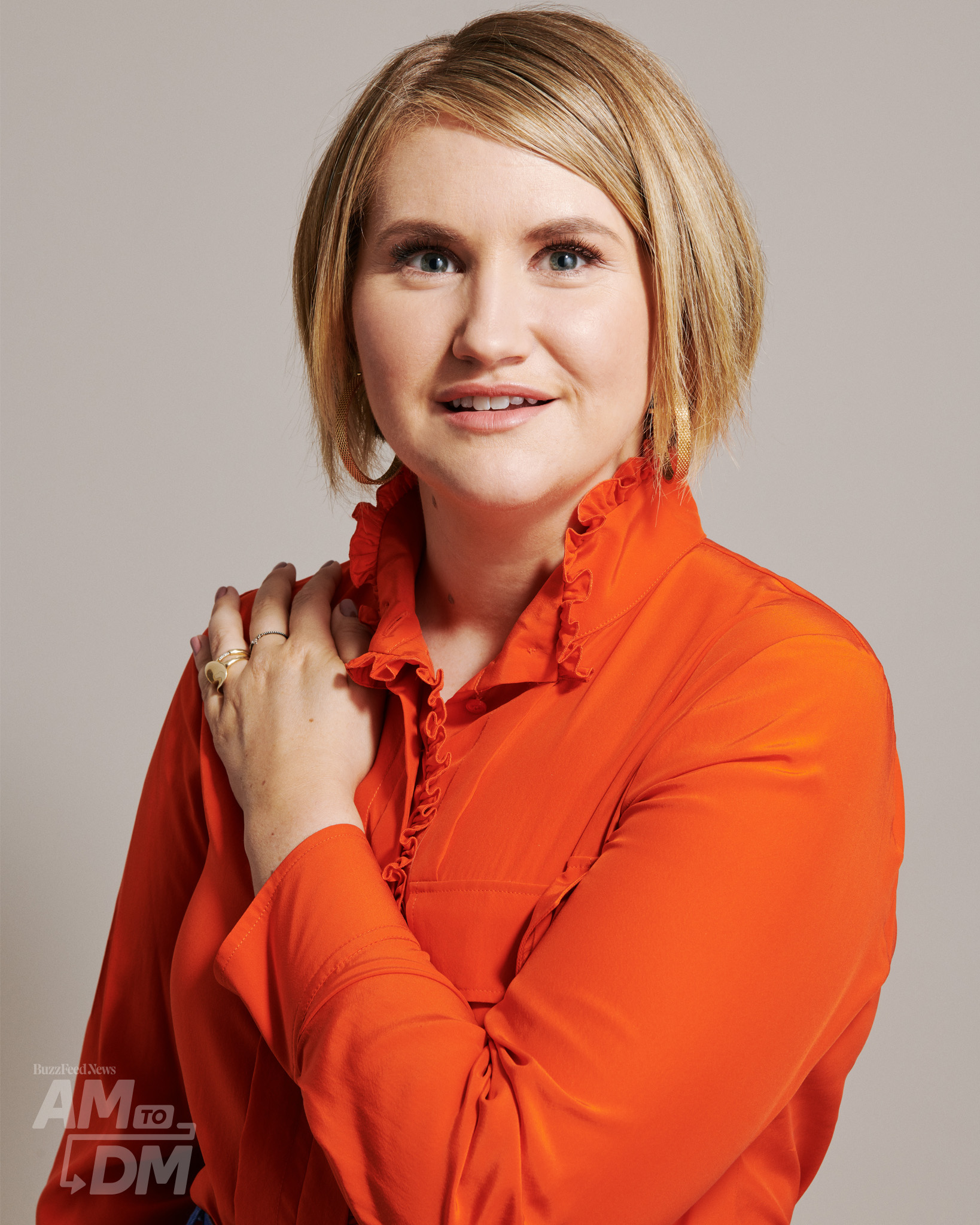 Portrait of Jillian Bell wearing a red blouse in front of a taupe background. CREDIT: JJ Reddington / BuzzFeed News
