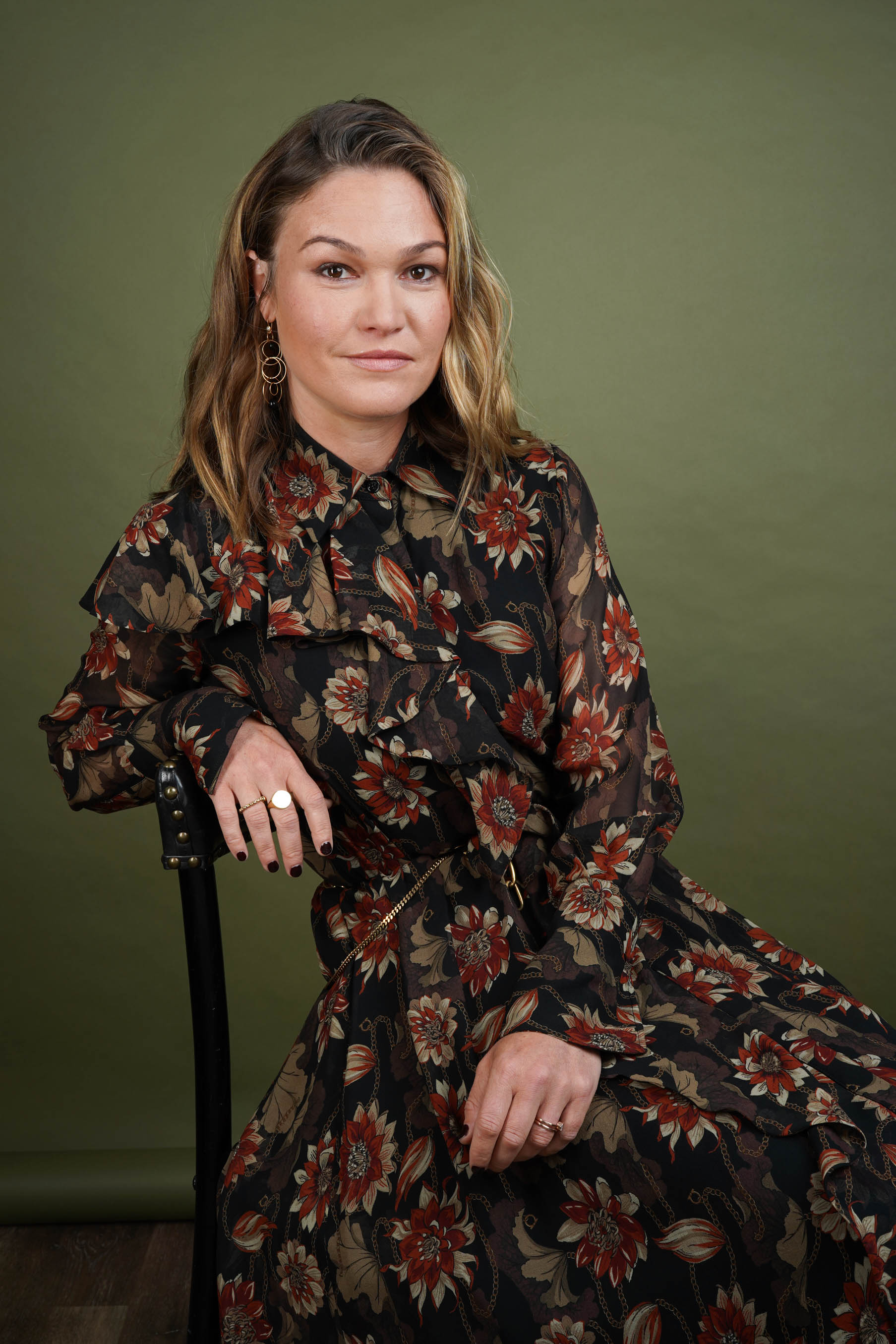 Portrait of Julia Stiles wearing a dark flora dress sitting in front of a green background. CREDIT: Erich Bartlebaugh / BuzzFeed News