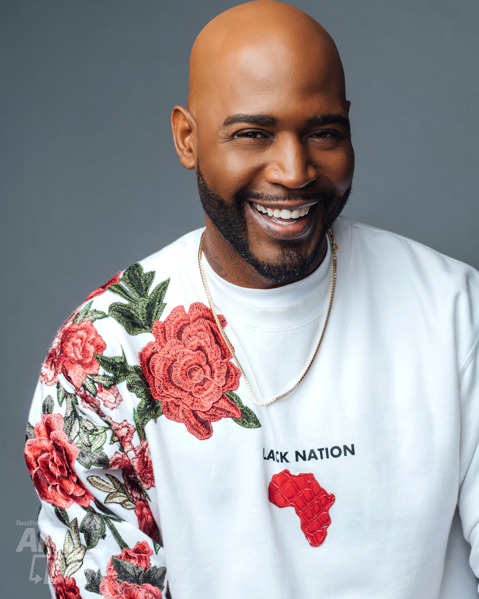 Portrait of Karamo Brown wearing a white sweatshirt with roses on it in front of a gray background. CREDIT: Taylor Miller / BuzzFeed News