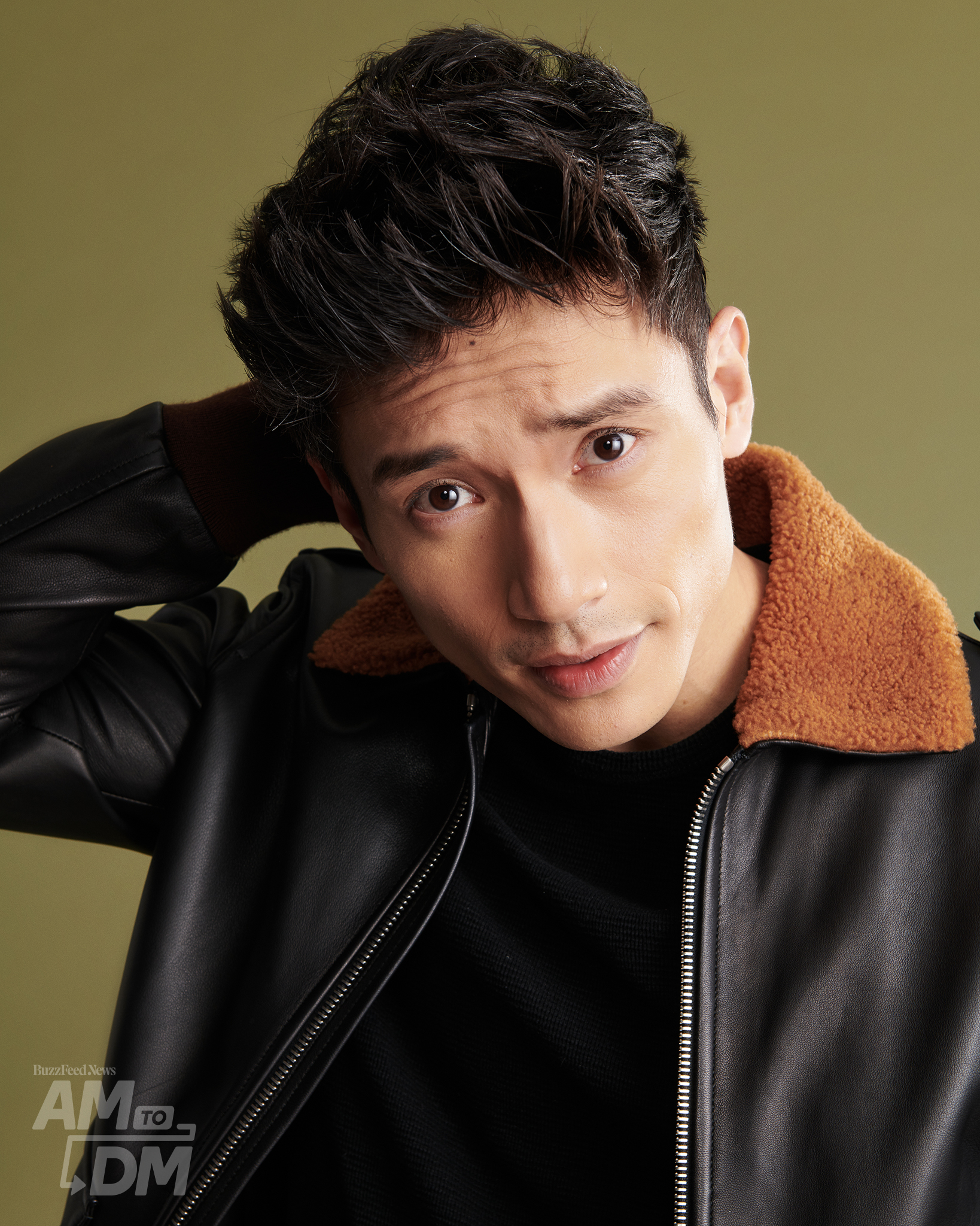 Portrait of Manny Jacinto wearing a leather jacket with brown trim in front of a green background. CREDIT: JJ Reddington / BuzzFeed News