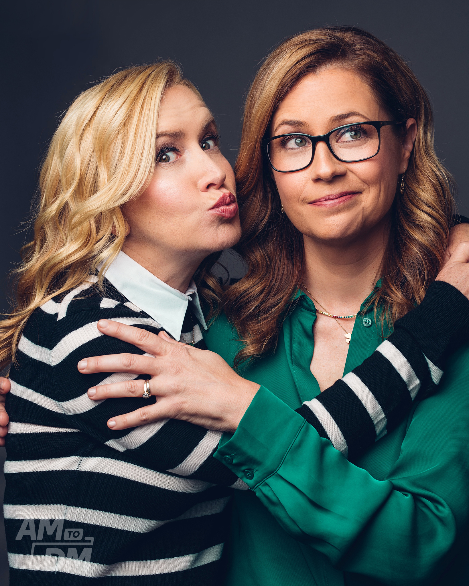 Portrait of Angela Kinsey wearing a black and white striped sweater and Jenna Fischer wearing a green blouse and glasses in front of a gray background. CREDIT: Taylor Miller / BuzzFeed News